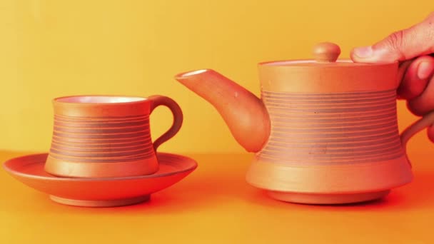 zbliżenie herbaty leje się z czajnika na pomarańczowym tle  - Materiał filmowy, wideo