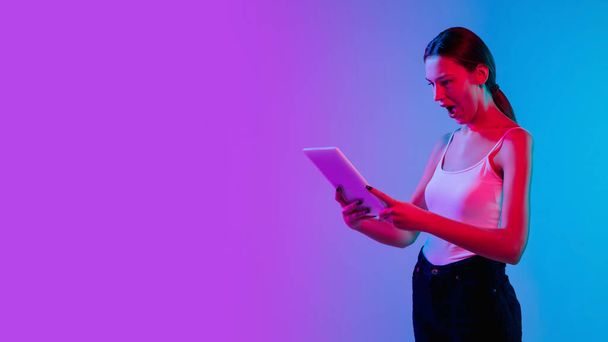 Mladé kavkazské ženy portrét na gradient blue-purple studio pozadí v neonovém světle - Fotografie, Obrázek