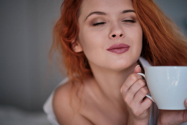 Beautiful young woman with cup of coffee at home - Fotoğraf, Görsel