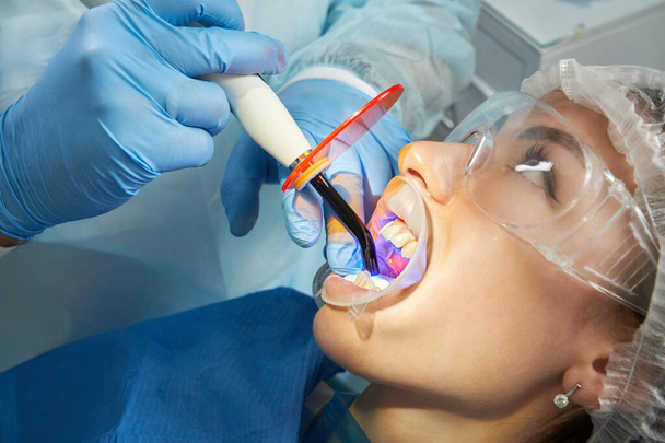Hammaslääkäri tekee toimenpiteen hampaiden kovettumisen UV-valo klinikalla - Valokuva, kuva