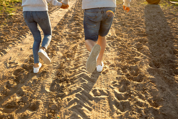 Neşeli ve mutlu çift kumlu bir yolda koşuyor. Gün batımında yürüyen güzel bir çift. Aşk ve ilişkiler - Fotoğraf, Görsel