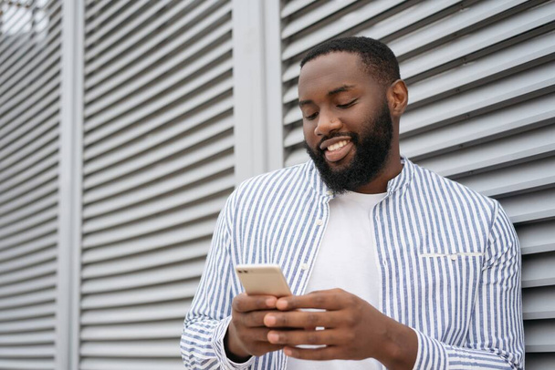  Африканский мужчина с помощью мобильного телефона, совершает покупки в Интернете - Фото, изображение
