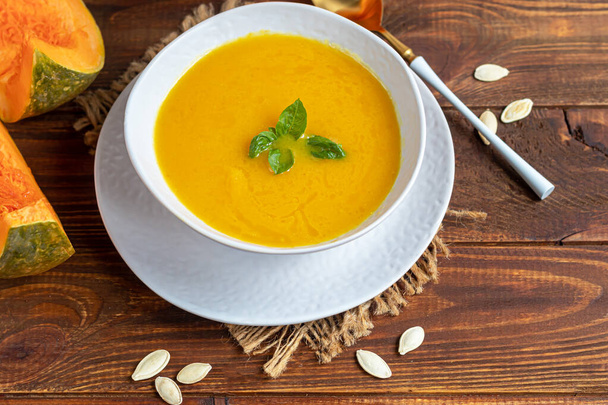 Fresh pumpkin cream soup with sour cream. Autumn lunch concept. On a wooden background. A dietary, healthy dish. Copy space. - Photo, image