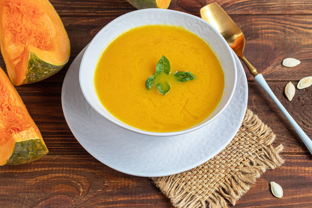 Fresh pumpkin cream soup with sour cream. Autumn lunch concept. On a wooden background. A dietary, healthy dish. Copy space. - Photo, Image