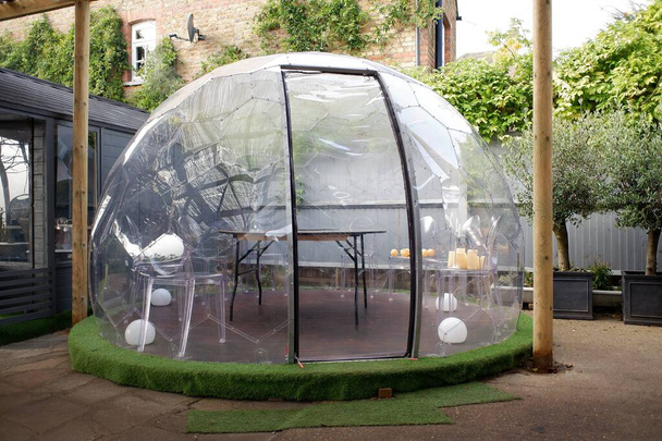 Coronavirus (Covid-19) salgını sırasında barın dışında yemek yemek için kullanılan plastik igloo çadırı. - Fotoğraf, Görsel