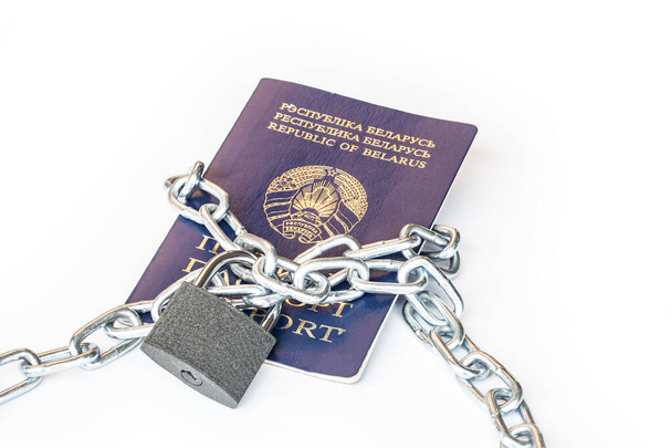 Studio lighting. the citizen's passport is tied with a metal chain in the center with a yellow lock. The concept of violation of the rights of citizens, a ban on movement. - Photo, Image