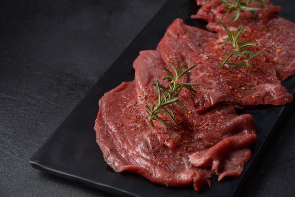 Raw beef steaks with spices and rosemary. - Photo, image