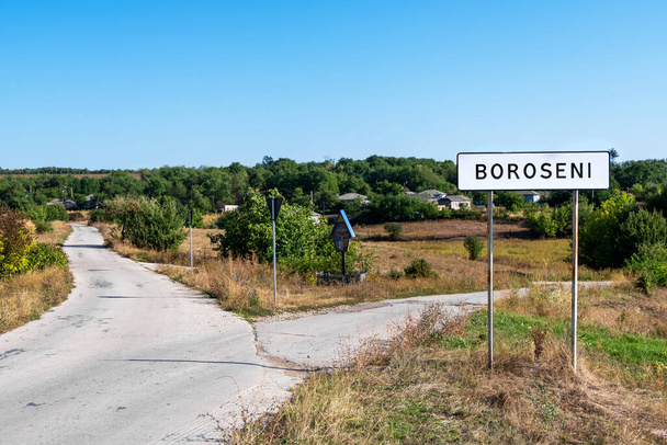 Señal de calle Boroseni en la carretera que se divide en dos maneras, vegetación y edificios en el fondo, Moldavia - Foto, imagen