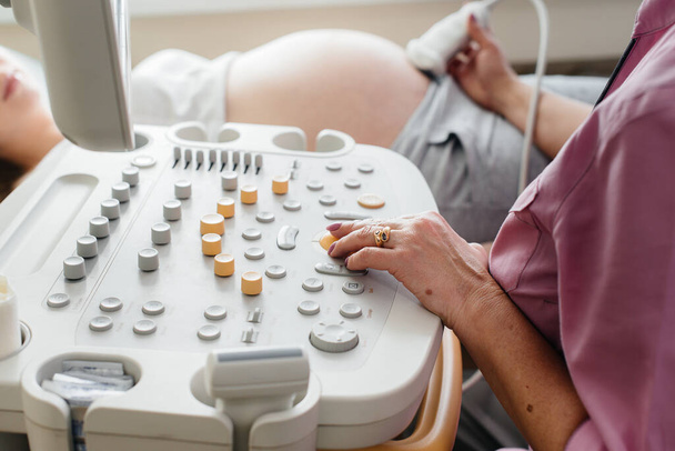 Close-up ultrasound device during a medical examination of a pregnant woman. Medical examination - Φωτογραφία, εικόνα