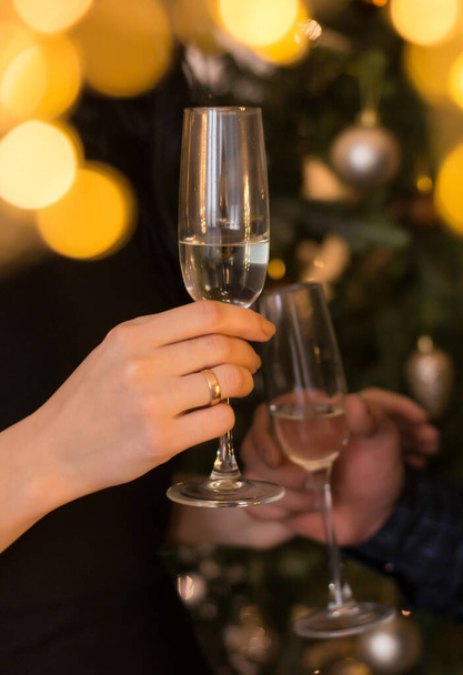 man and woman clink glasses of champagne against the background of a christmas tree - Photo, Image