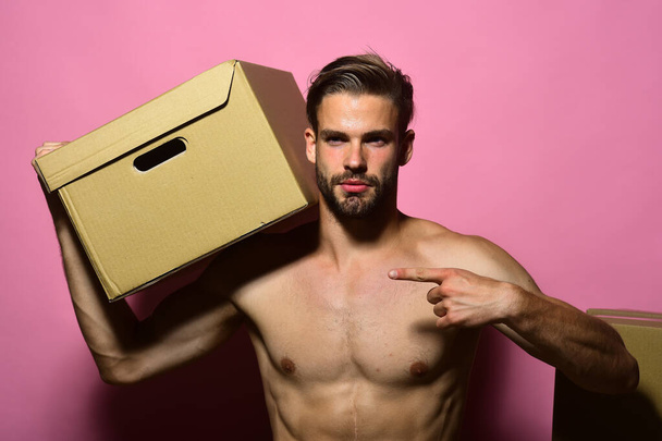 Guy with attractive naked torso stands near boxes. - Foto, afbeelding
