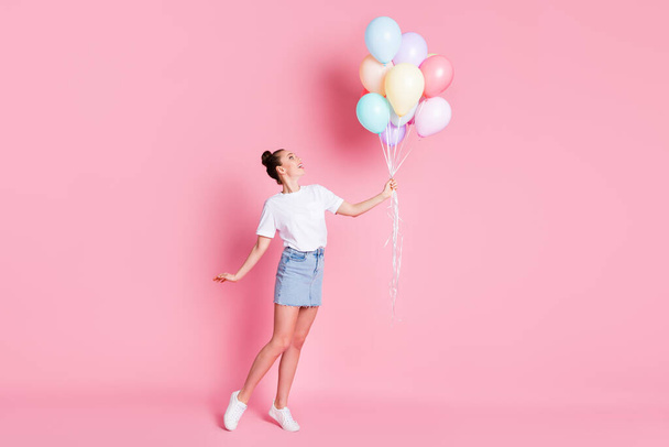 Full length photo of attractive pretty lady pretty bun summer vacation good mood hold many air balloons celebration wear white t-shirt mini skirt shoes isolated pink color background - Fotografie, Obrázek