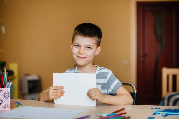A school-age boy does homework at home. Training at school - 写真・画像