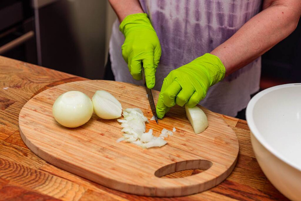 Close up view of female hands peeling onions. Cooking concept. - Photo, Image