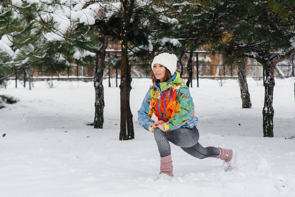 A young athletic girl is warming up before running on a frosty day. Fitness, running - Фото, изображение