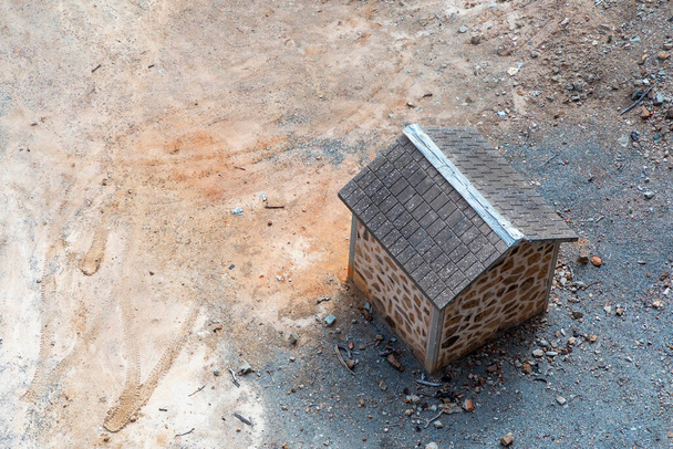 Un piccolo edificio in mattoni marroni con tetto piastrellato su sporcizia asciutta circondato da rocce - Foto, immagini