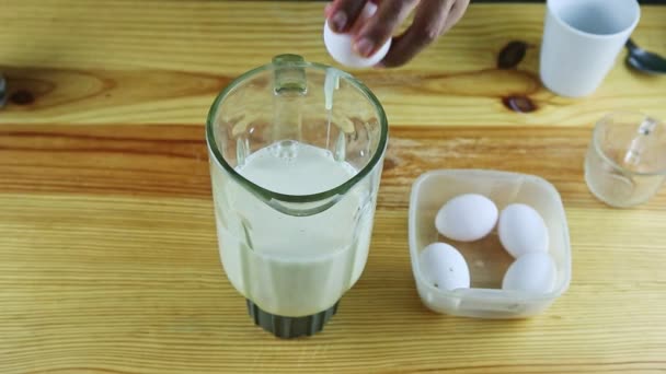 top view on man by hands breaks raw eggs into big glass blender chalice with milk - Footage, Video