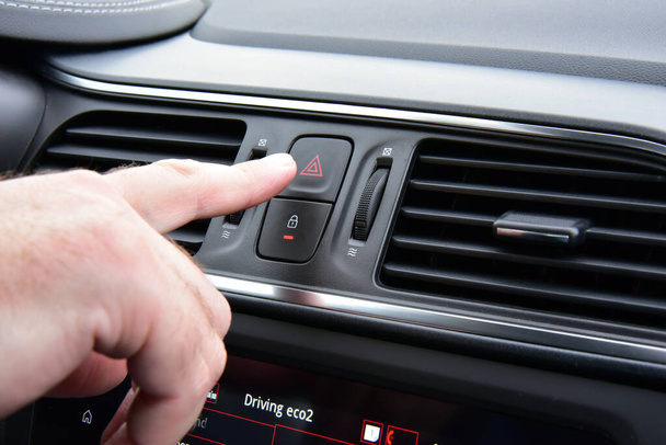 Человек нажимает красным треугольником кнопку предупреждения опасности автомобиля - Фото, изображение