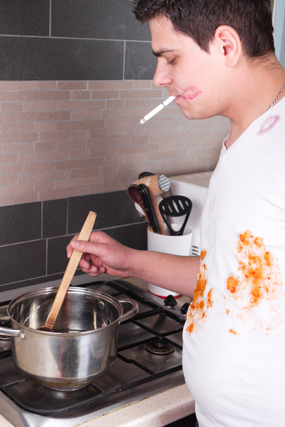 knappe jongeman koken en roken - Foto, afbeelding