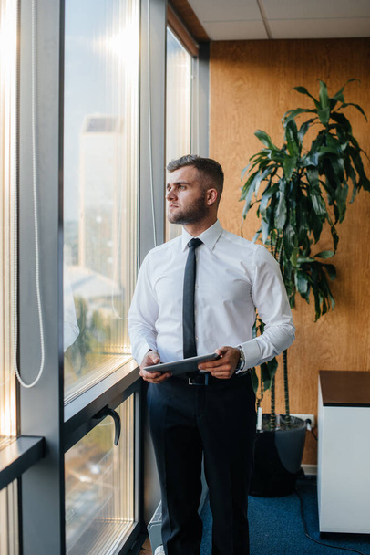 An employee in the office is standing near the window. Finance - Valokuva, kuva