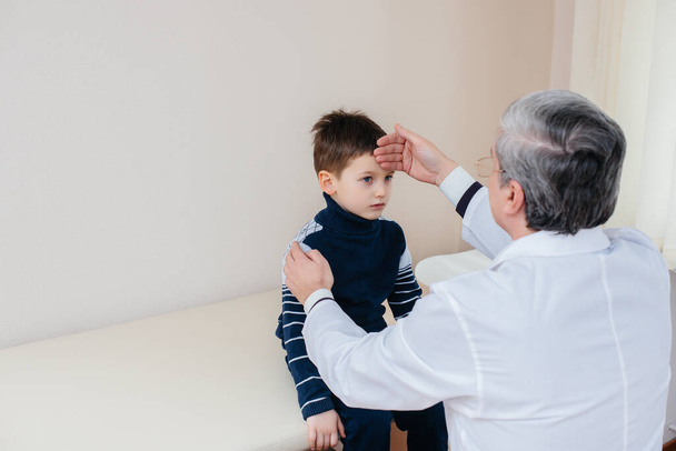 A young boy is listened to and treated by an experienced doctor in a modern clinic. A virus, and an epidemic - Photo, Image