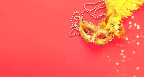 Золотая карнавальная маска на розовом фоне с серебряными бобами. Творческое пространство для дизайна. Крупный план - Фото, изображение