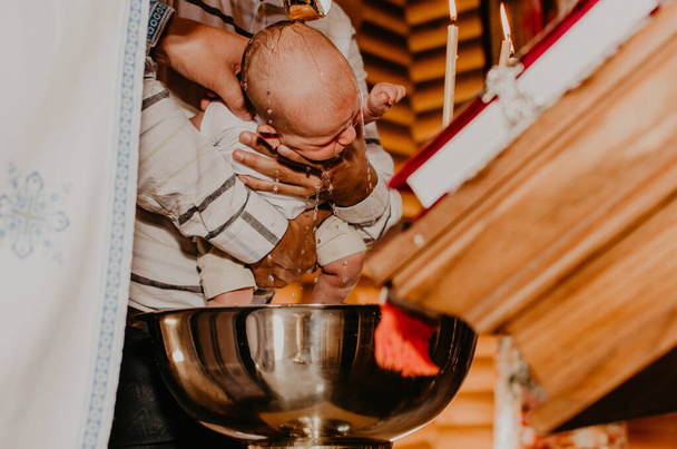 Священник омывает ребенка святой водой. обряд таинства озарения - Фото, изображение