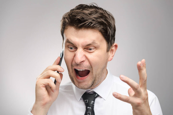 Naštvaný muž křičí na klienta po telefonu. Agresivní šéf volá zaměstnance, který nedokončil svou práci včas. - Fotografie, Obrázek