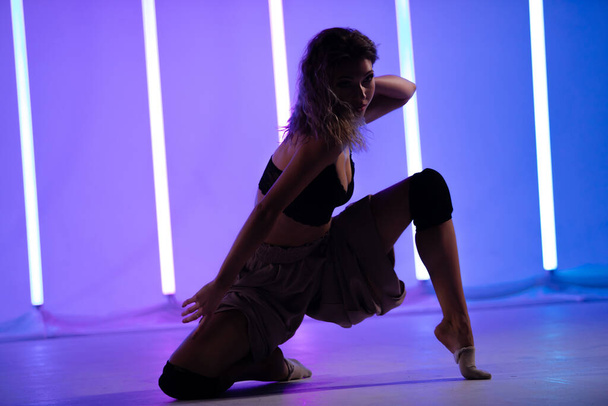 Portrait of a female contemporary dancer posing in the studio against the backdrop of neon lamps. Woman dancing beautiful pose isolated background. - Foto, imagen
