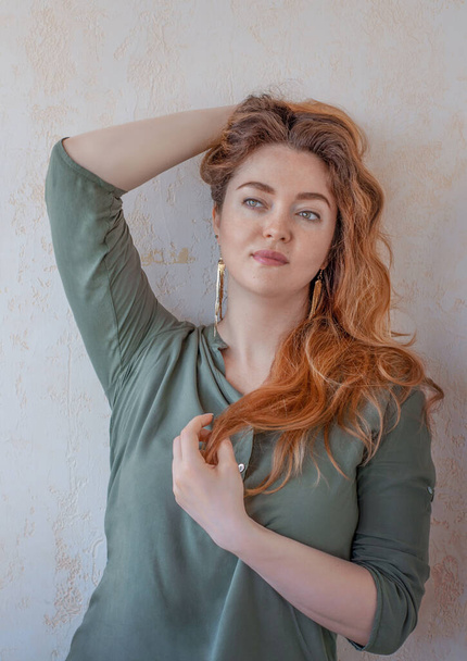 A red-haired girl with green eyes. Curls. Beautiful hair.The green blouse. close-up portrait. face. - Foto, Imagen