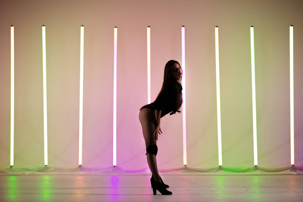 Brunette with red lips posing in a sexy pose against the backdrop of neon lights. - Foto, imagen