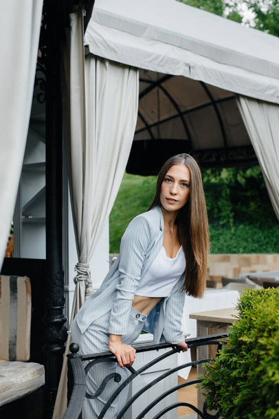 A beautiful young girl is standing on the veranda of a beautiful house. - Fotografie, Obrázek