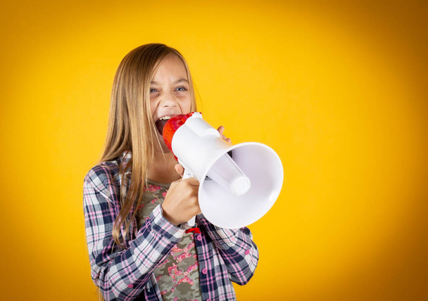 little girl, with megaphone, yellow background, scream - Фото, изображение