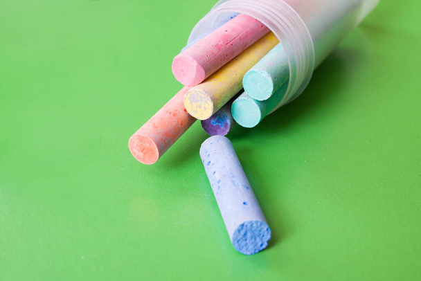 Container with multicolored crayons on a green background - Photo, Image
