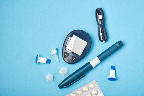 set diabético de monitor de medidor de glucosa, lanceta con agujas de repuesto, jeringa para inyección de insulina y comprimidos, nuevas agujas estériles para inyección, fondo azul, vista superior del lugar de copia - Foto, imagen