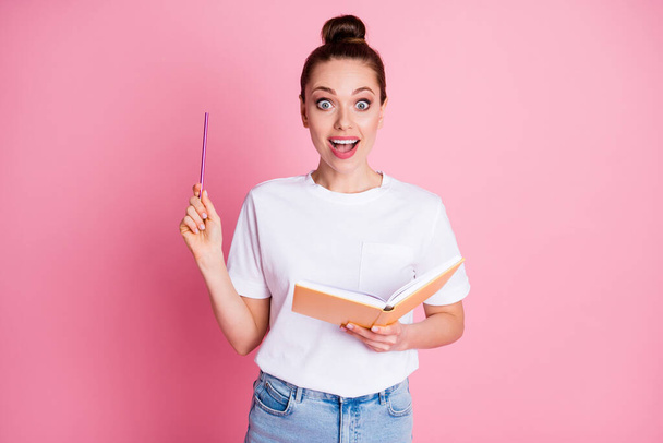 Photo of astonished positive girl write copybook think thoughts get incredible idea raise pencil up scream wow omg wear white t-shirt denim jeans isolated over pastel color background - Fotó, kép