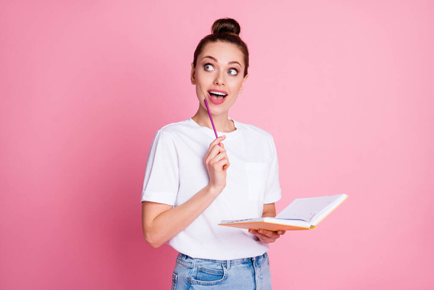 Photo surprised shocked girl write copybook essay think thoughts get incredible idea scream touch pencil chin look copyspace wear white t-shirt denim jeans isolated pastel color background - Foto, immagini