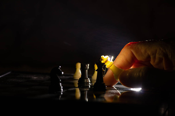 το χέρι μιας γριάς και το σκάκι στο σκοτάδι, παίζοντας σκάκι - Φωτογραφία, εικόνα