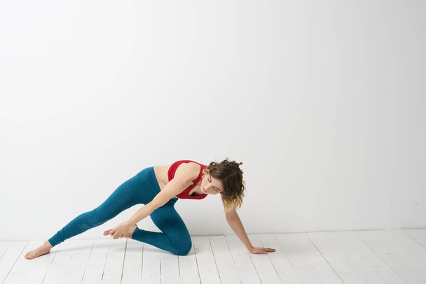 Жінка в блакитних джинсах практикує йогу на світлому фоні в приміщенні і тонку фігуру в гімнастиці
 - Фото, зображення