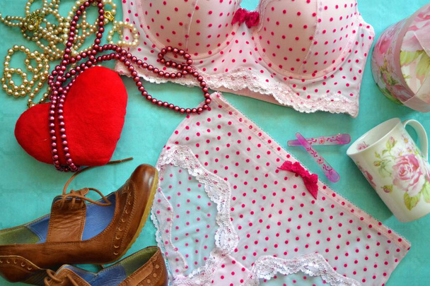 Detailní záběr vysokých podpatků se srdcem, perleťovými náhrdelníky a dámským spodním prádlem v pozadí symbolizujícím přípravu rande - Fotografie, Obrázek