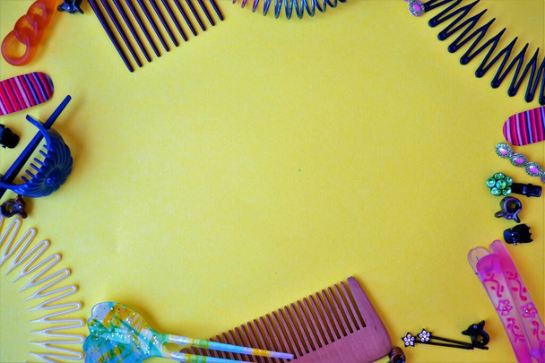 Telaio su fondo giallo composto da elementi di acconciatura come pettine, clip e forcine colorate o fasce per capelli - Foto, immagini