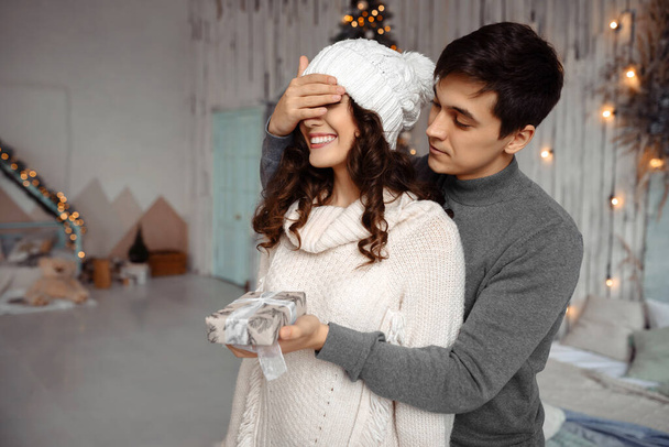 Erkek, Noel hediyesi verirken sevgilisinin gözlerini kapatır, romantik bir sürpriz. - Fotoğraf, Görsel