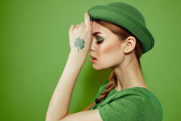 Menina agradável com um shamrock na mão em um fundo verde feriados St. Patricks Dia chapéu divertido em sua cabeça  - Foto, Imagem