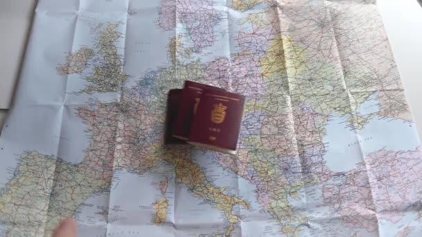 Cestovní pasy a různé měny v plastovém sáčku jsou házeny na barevnou mapu Evropy. Většina Evropy je v rámu. Krátký klip pro ilustraci cestování a cestovního ruchu. Zpomalený pohyb 1080p stock záběry Brian Holm Nielsen - Záběry, video
