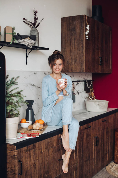 Lovely woman with coffee in kitchen. Christmas morning - 写真・画像