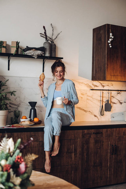 Smiling girl with coffee and croissant. Christmas morning - Photo, Image
