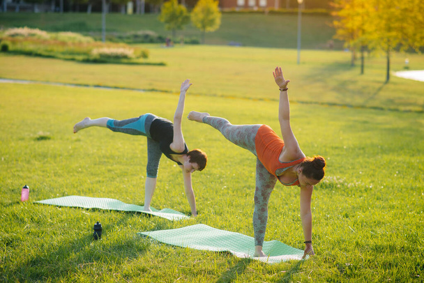 Young girls do yoga outdoors in the Park during sunset. Healthy lifestyle - Photo, image