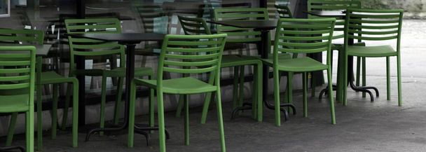 緑の椅子とテーブルが並ぶ都会の風景 - 写真・画像