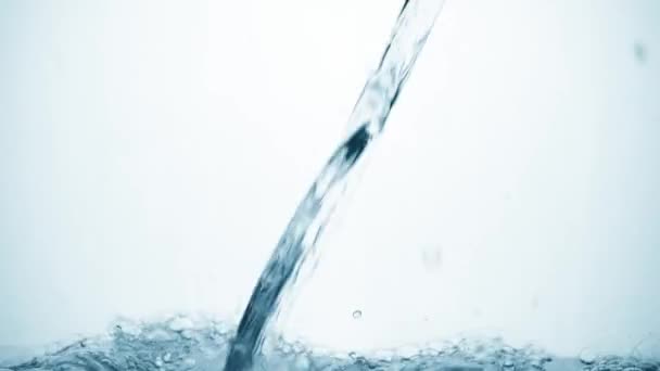 Λαμπρή ροή του νερού σε αργή κίνηση πέφτει στην ομαλή καθαρή επιφάνεια, δημιουργώντας φυσαλίδες αέρα, πτώση πιτσιλιές και κυματισμούς μετά την πτώση, πλευρική άποψη. Φρεσκάδα ενός διαυγούς μπλε υγρού σε λευκό φόντο. - Πλάνα, βίντεο