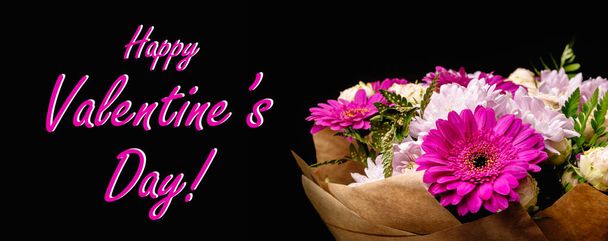 Grote mooie boeket van chrysanten, gerbera 's, rozen en varens in roze en paarse kleuren, verpakt in bruin ambachtelijk papier op een zwarte achtergrond. Briefkaart voor de gelukkige Valentijnsdag. - Foto, afbeelding